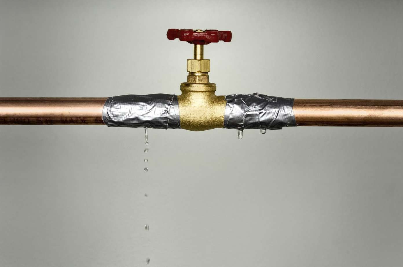 Closeup shot of the leaking water pipe with red valve
