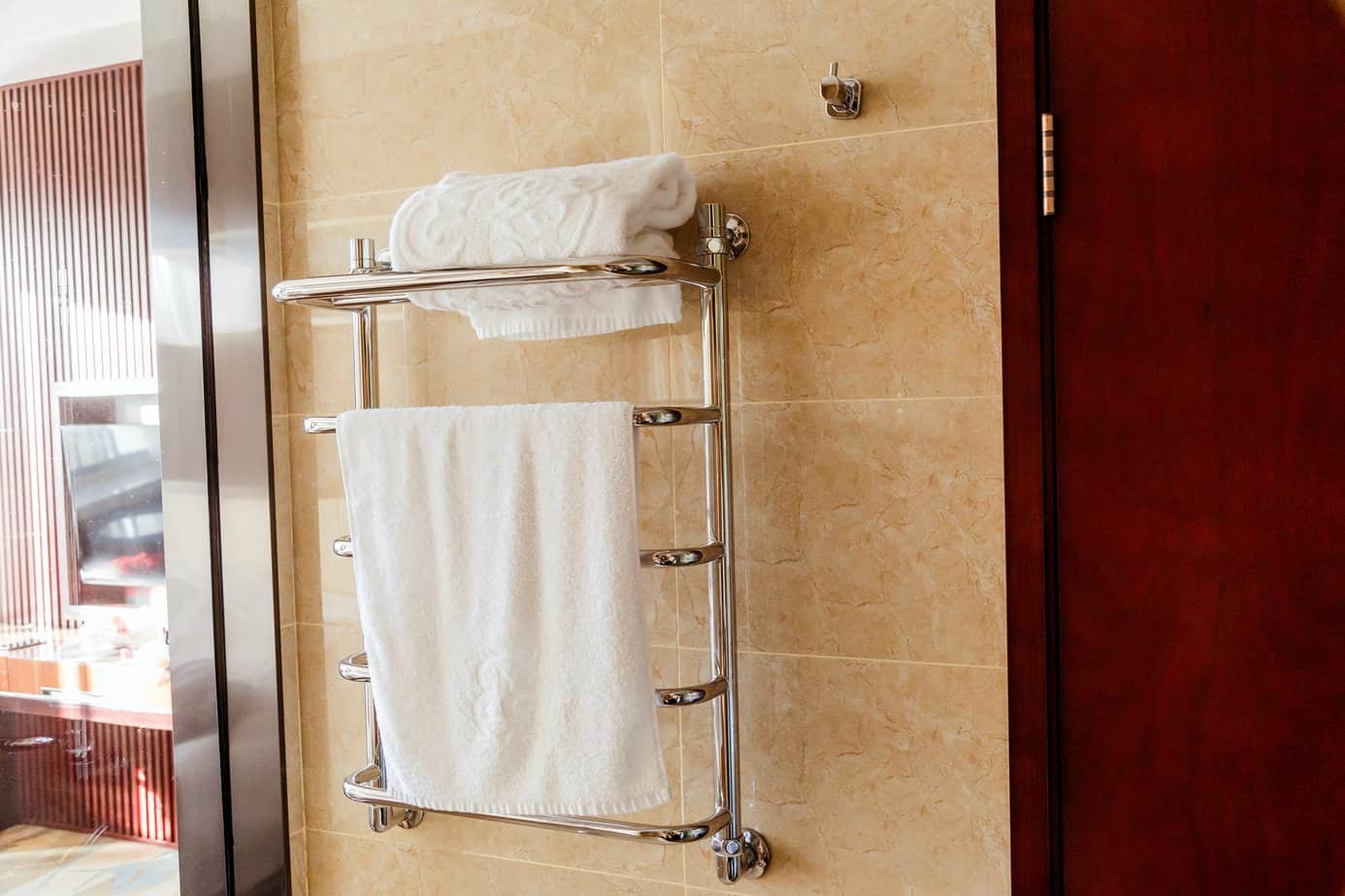 Modern heated towel rail on tiled bathroom wall.