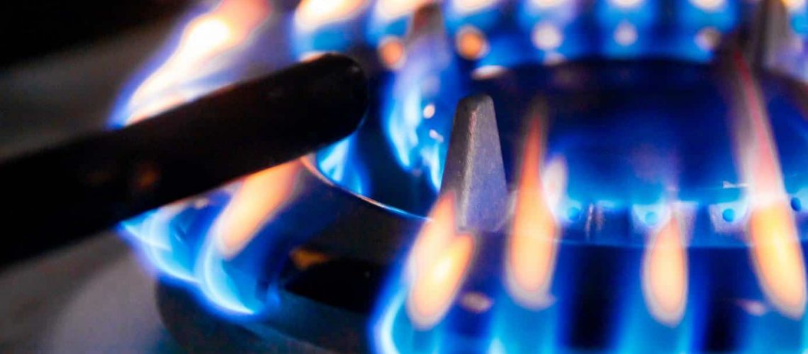 Macro closeup of modern luxury gas stove top with blue fire flame knobs